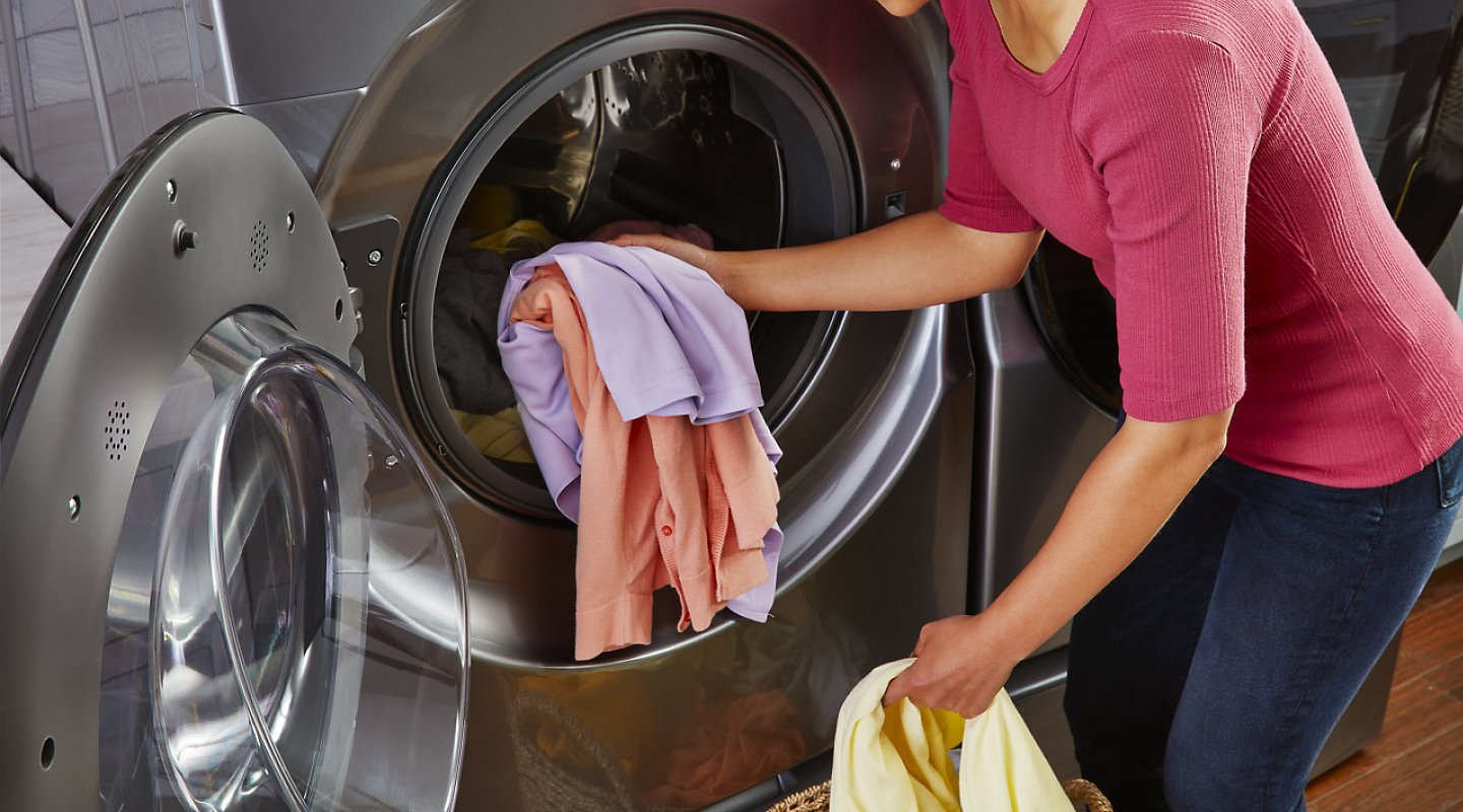 Person putting clothing inside laundry machine