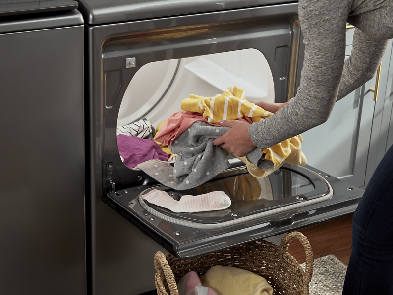 Person loading clothes into a Whirlpool® dryer