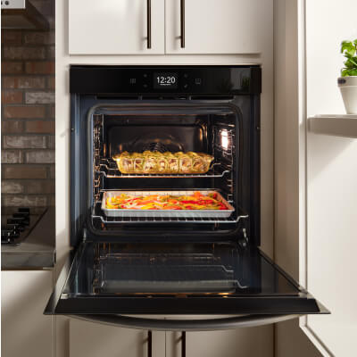 Black Whirlpool® single wall oven with food inside set into white cabinets. 