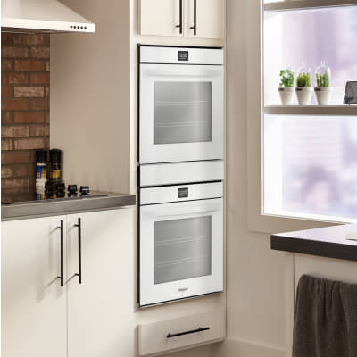 Whirlpool® stainless steel double wall oven set into white cabinets