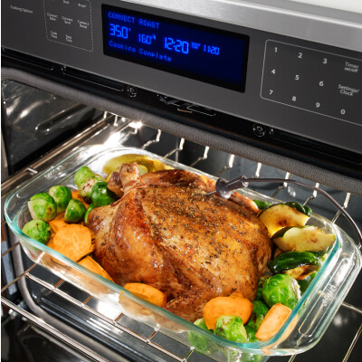 Turkey roasting in pan with veggies inside oven