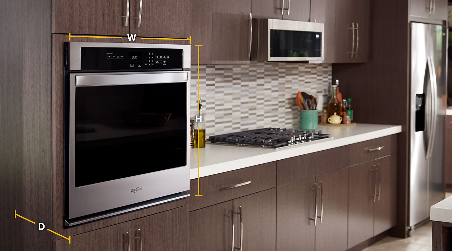 Whirlpool® stainless steel single wall oven set into wood finished cabinets with diagram of width, height and depth.