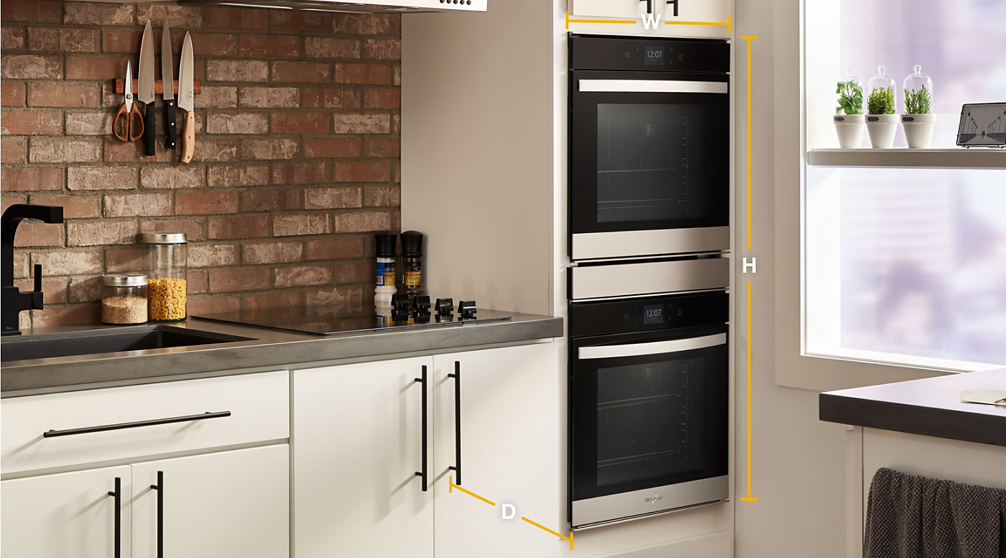 Whirlpool® stainless steel double wall ovens set into white cabinets with diagram of width, height and depth