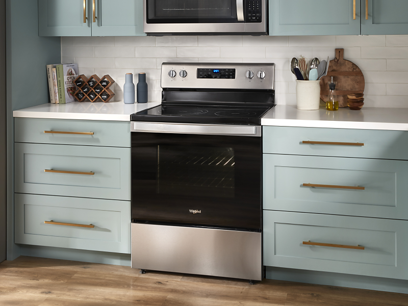 A stainless steel KitchenAid® gas range with pistachio-colored cabinets on either side.