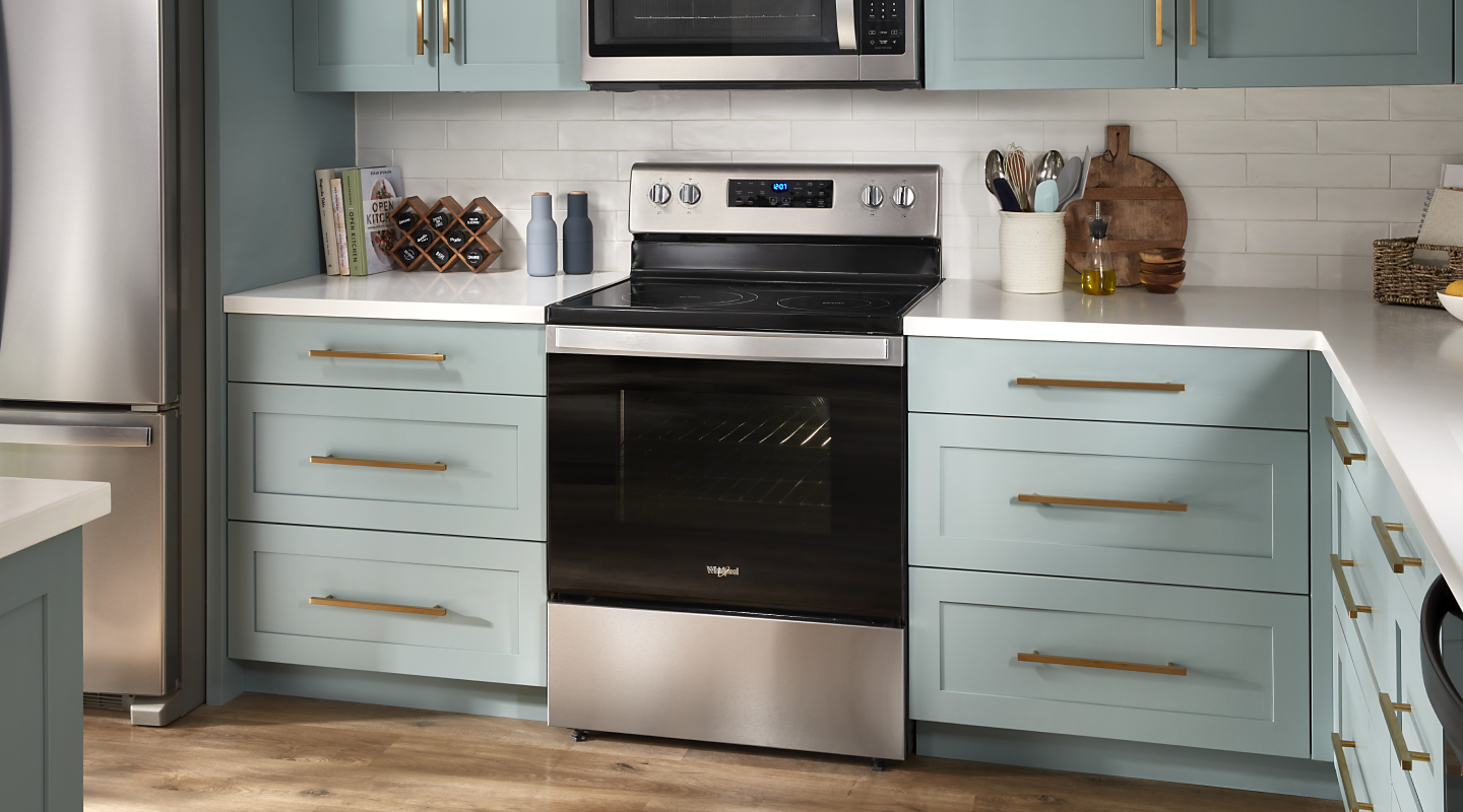 A stainless steel KitchenAid® gas range with pistachio-colored cabinets on either side.
