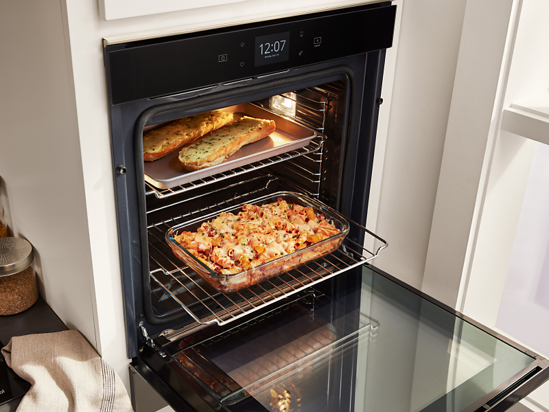 Casserole and garlic bread cooking inside a Whirlpool® wall oven