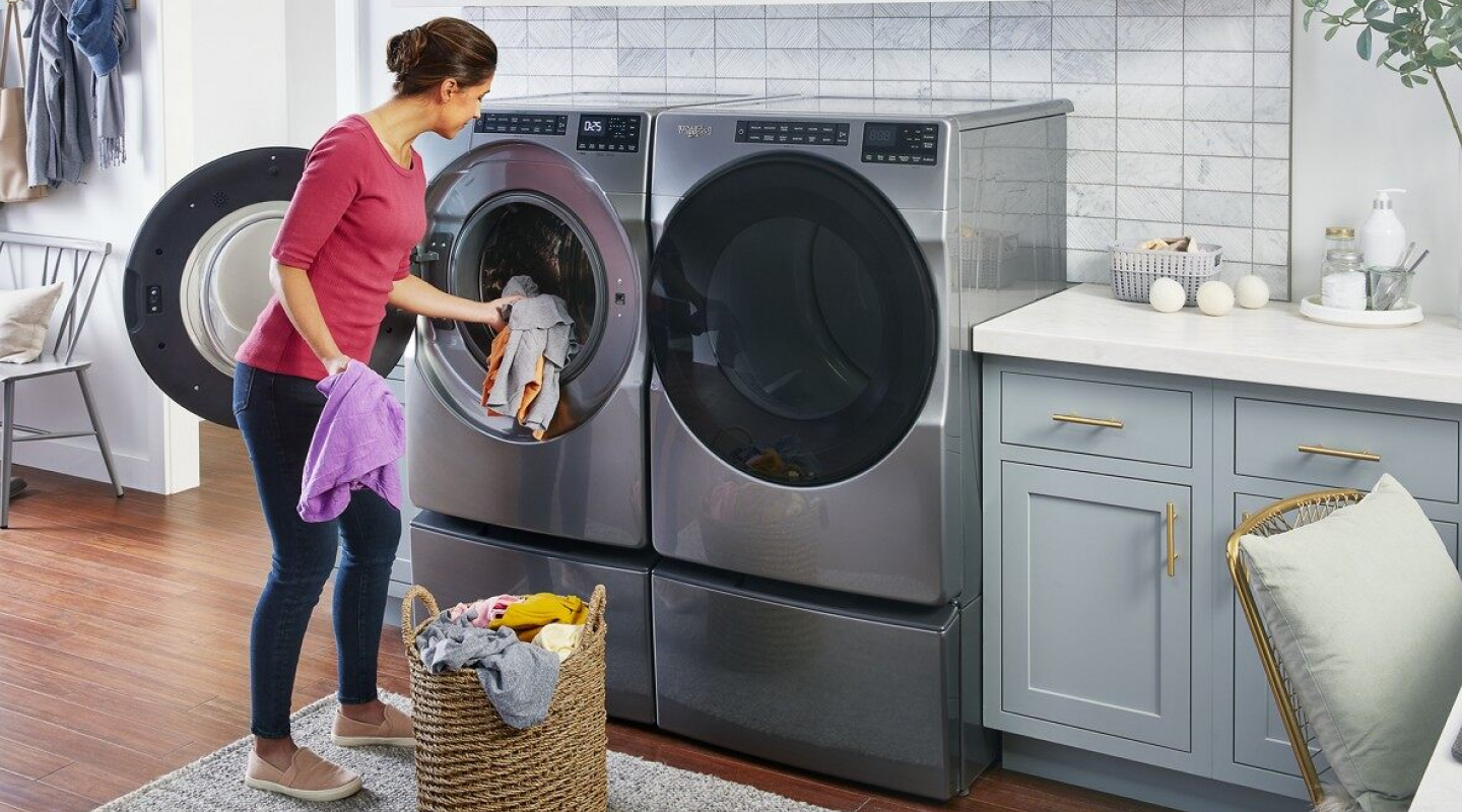 Person loading laundry in a Whirlpool® front load dryer