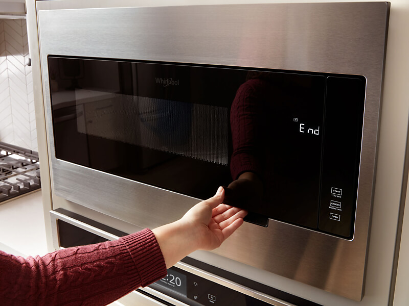 Person opening a Whirlpool® microwave