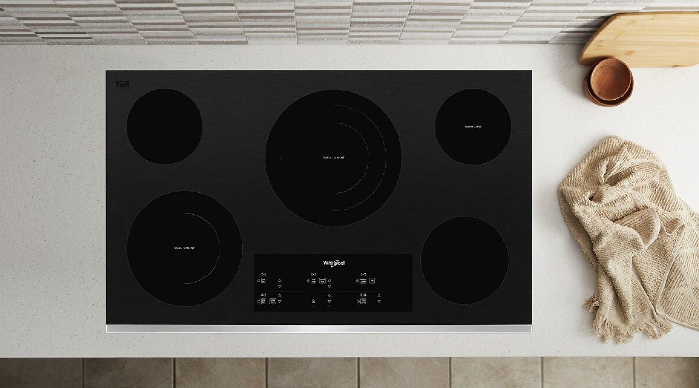 A Whirlpool® Electric Cooktop with a towel next to it.