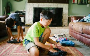 A child folding clean laundry in a living room