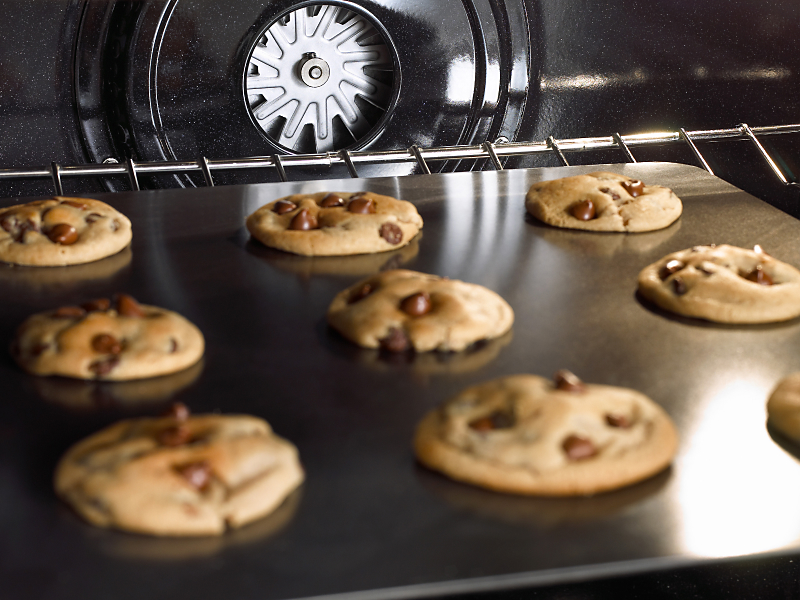 A sheet of chocolate chip cookies baking in an oven.