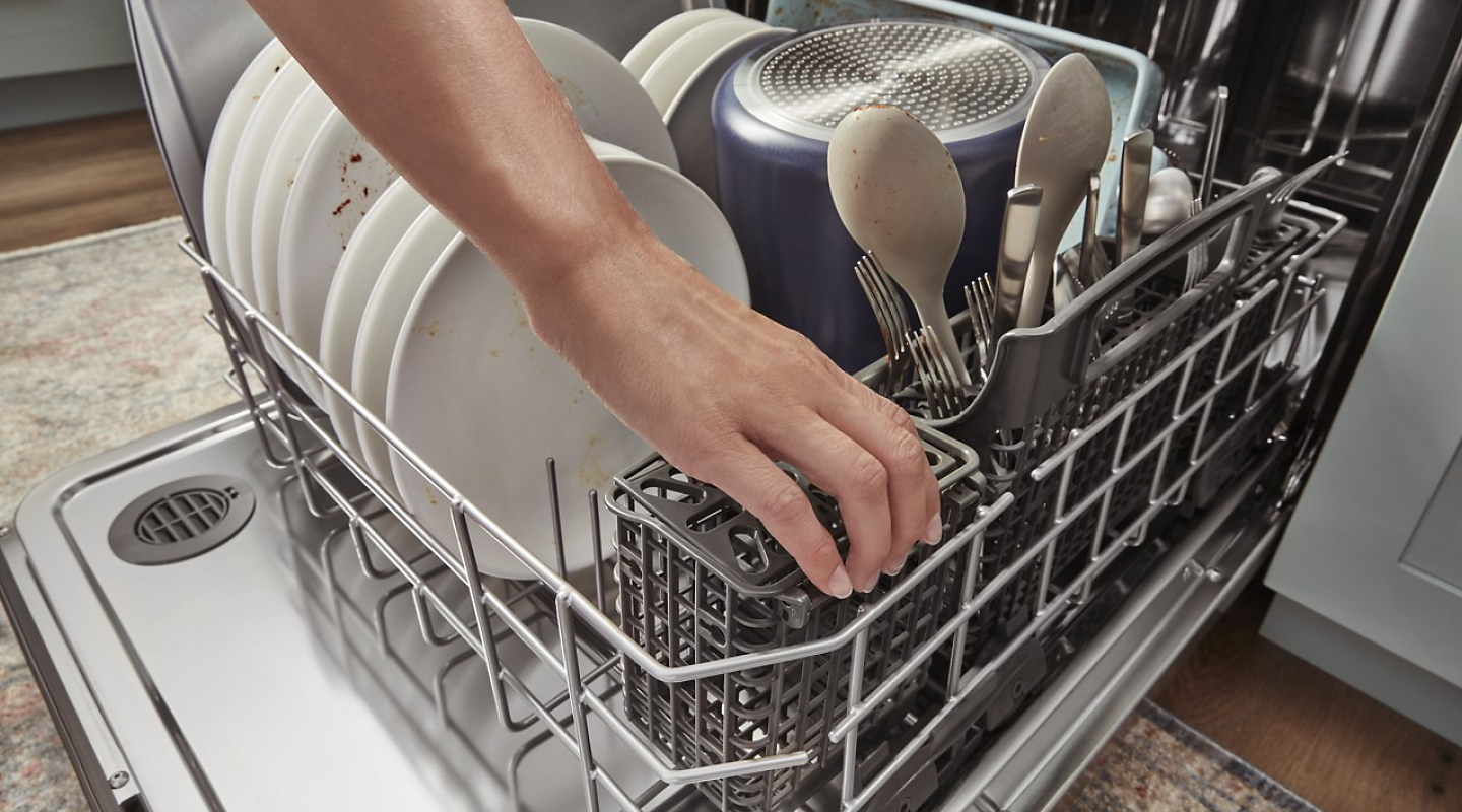 Hand reaching into a full dishwasher
