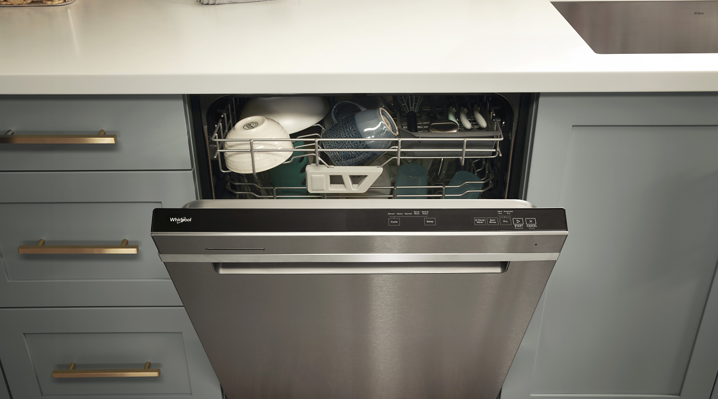 A loaded Whirlpool® dishwasher with an open door