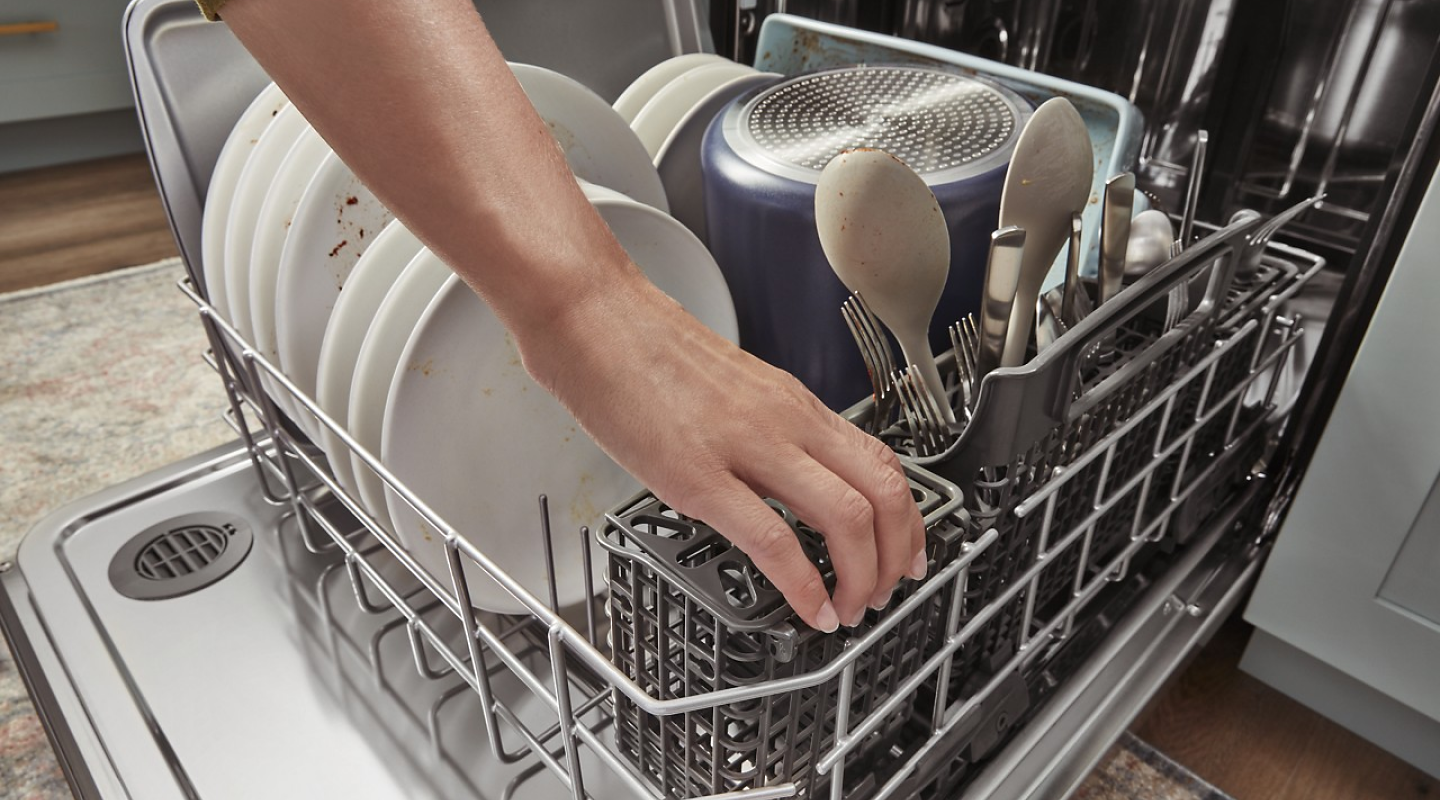 A dishwasher rack being loaded with dirty dishes