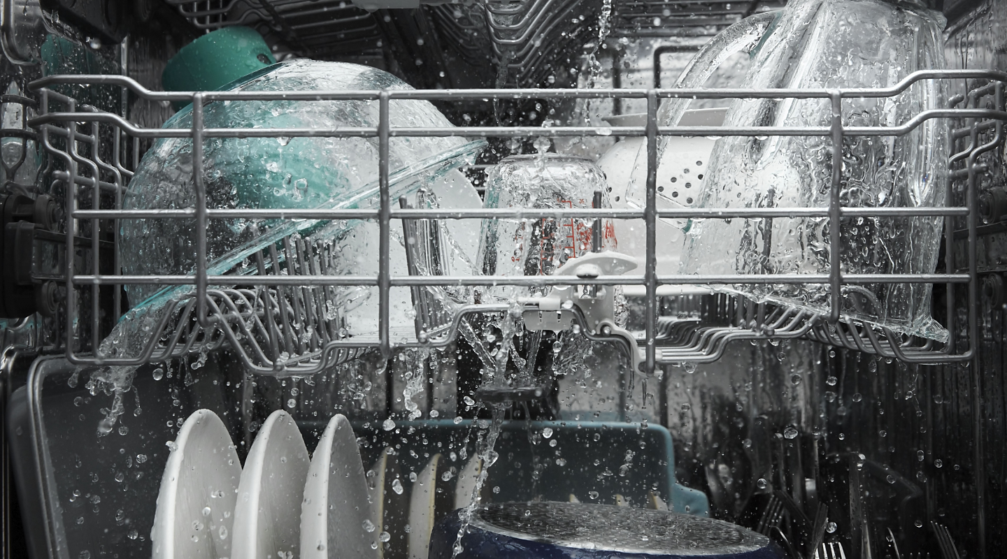 Dishes being rinsed with water inside a dishwasher