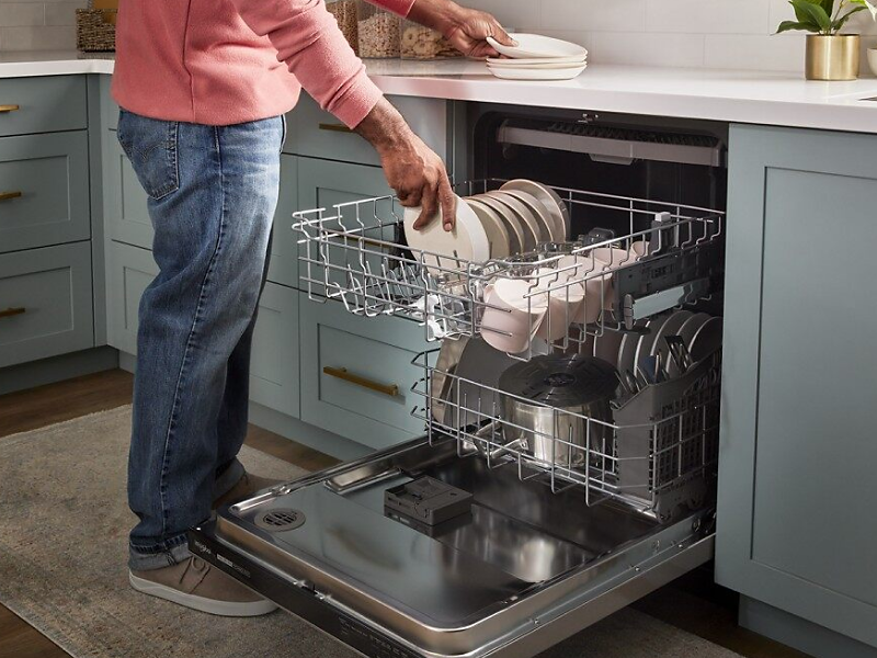 A person loading dishes into a dishwasher
