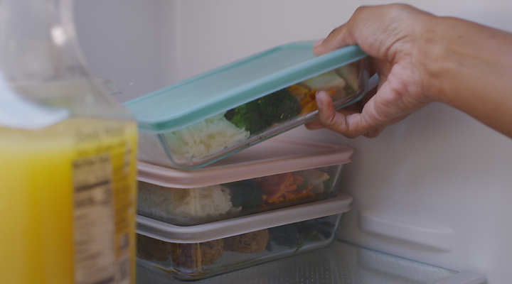 A person placing leftovers in the fridge