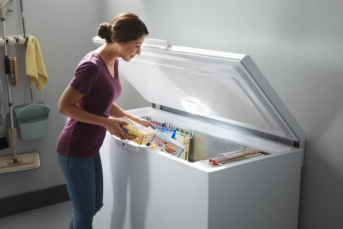 Person placing items in a white chest freezer 