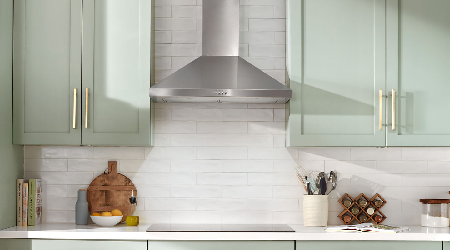 A stainless steel range hood above a cooktop 