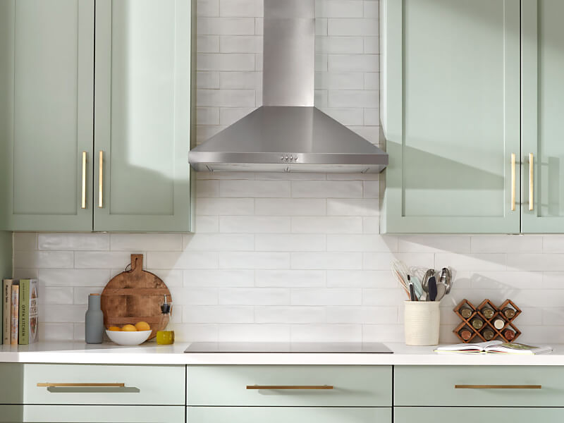 A stainless steel range hood above a cooktop 