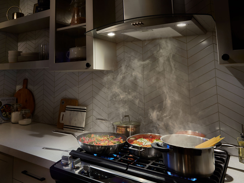 A range hood drawing up smoke from various dishes