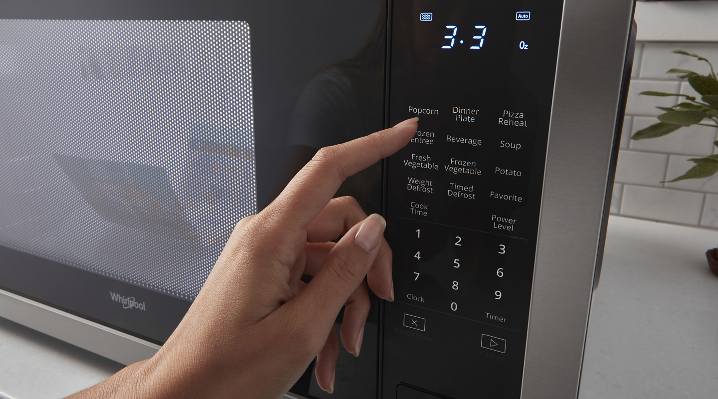 Person selecting settings on a microwave touchpad 