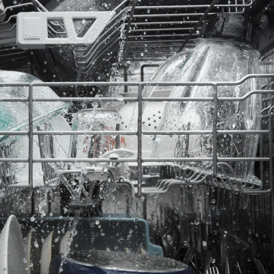A closeup of the upper rack of a Whirlpool® dishwasher washing dishware during a wash cycle.