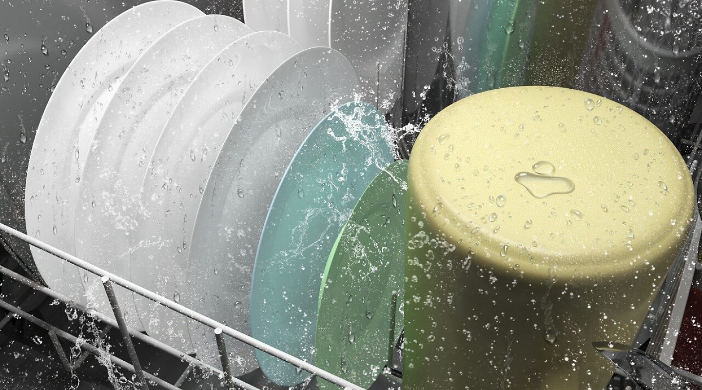 A closeup of the bottom rack of a Whirlpool® dishwasher washing dishware during a wash cycle.