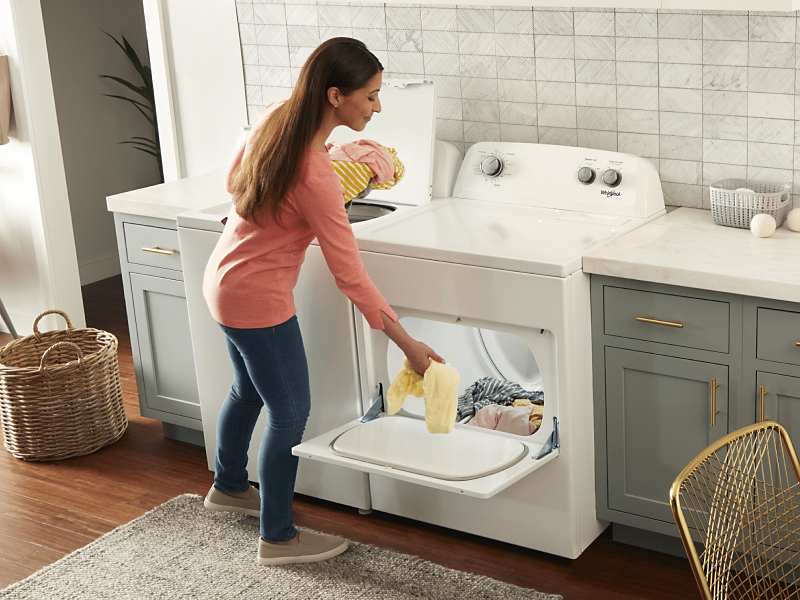Person placing clothes into a Whirlpool® front load dryer.