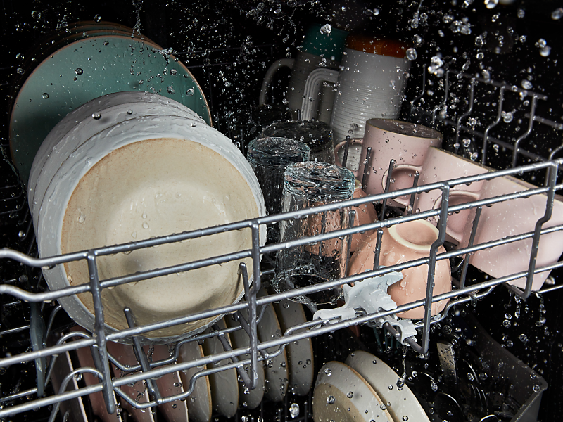 The interior of a Whirlpool® dishwasher cleaning dishes during a wash cycle.