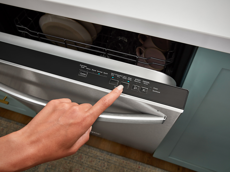 Person selecting a wash cycle on a Whirlpool® top control dishwasher