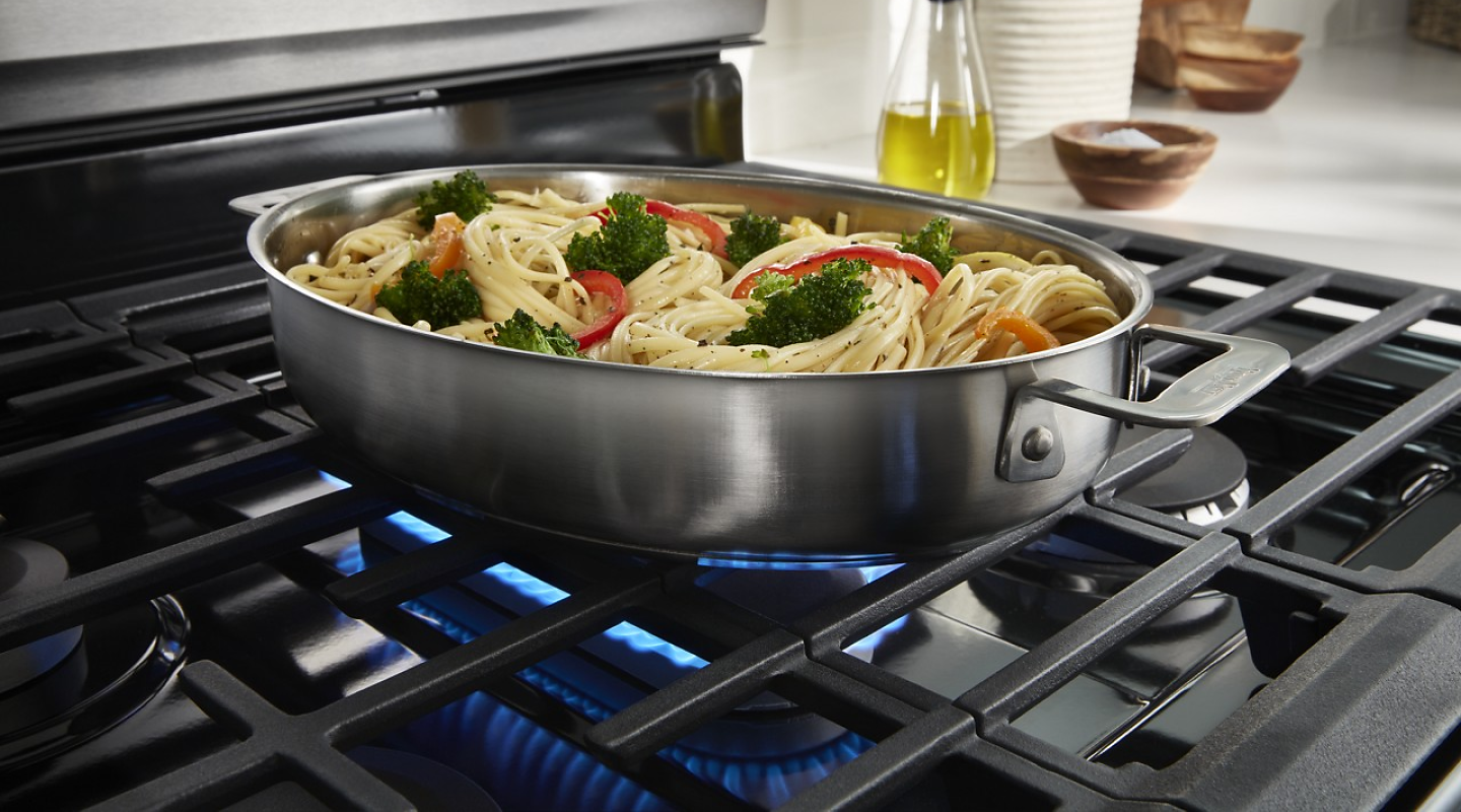 A pasta dish with vegetables cooking on a gas range burner