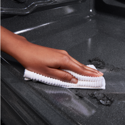 Person cleaning an oven with a white cloth