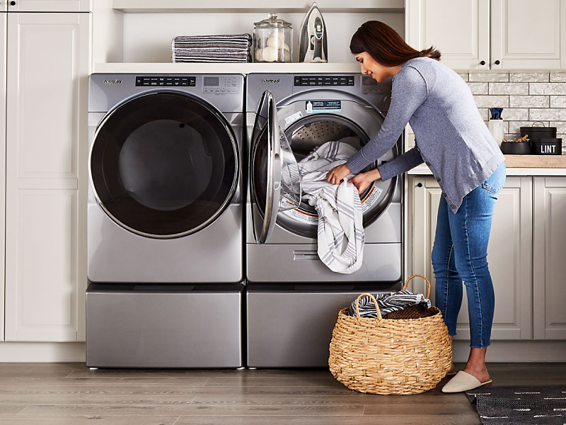 Woman loading towels into a Whirlpool® stainless steel dryer