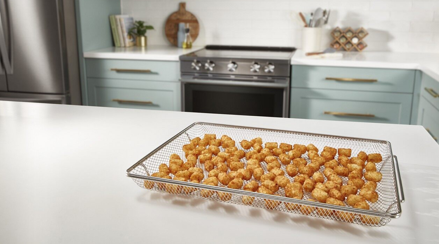 A basket with air fried food on a counter in a modern kitchen.