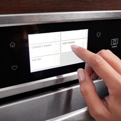 Person selecting "Keep Warm" setting on oven display screen.