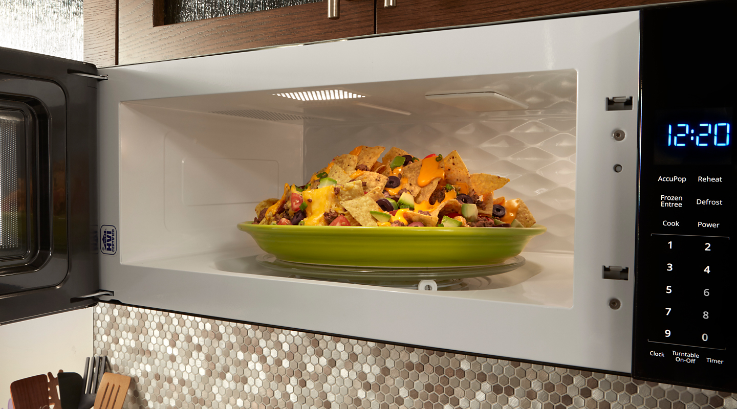 Green plate of nachos inside over-the-range microwave