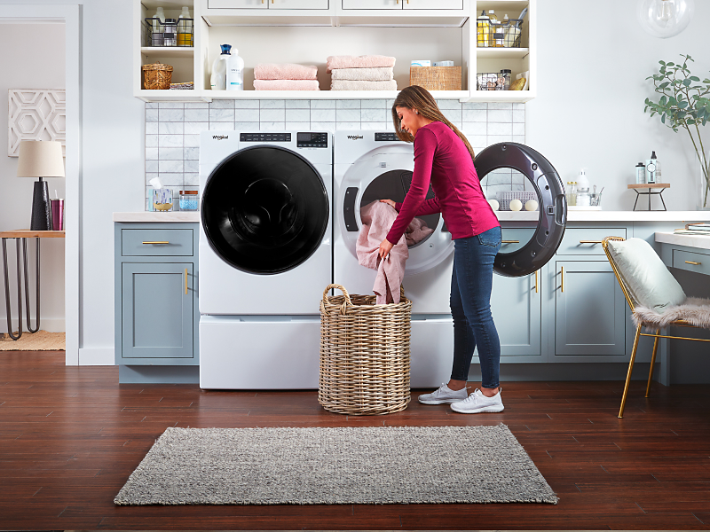 Woman unloading laundry from a white Whirlpool® dryer