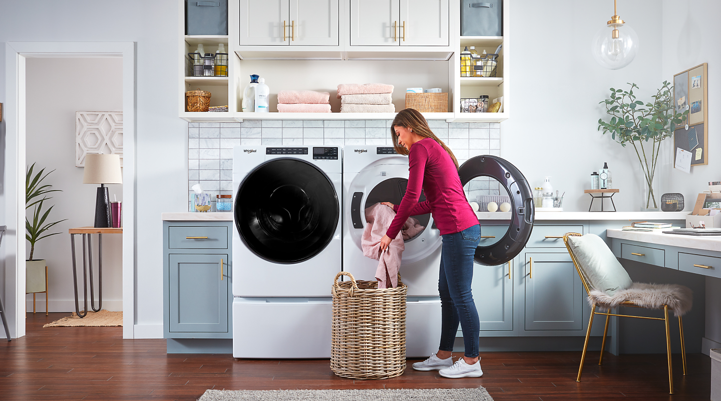 Woman unloading laundry from a white Whirlpool® dryer