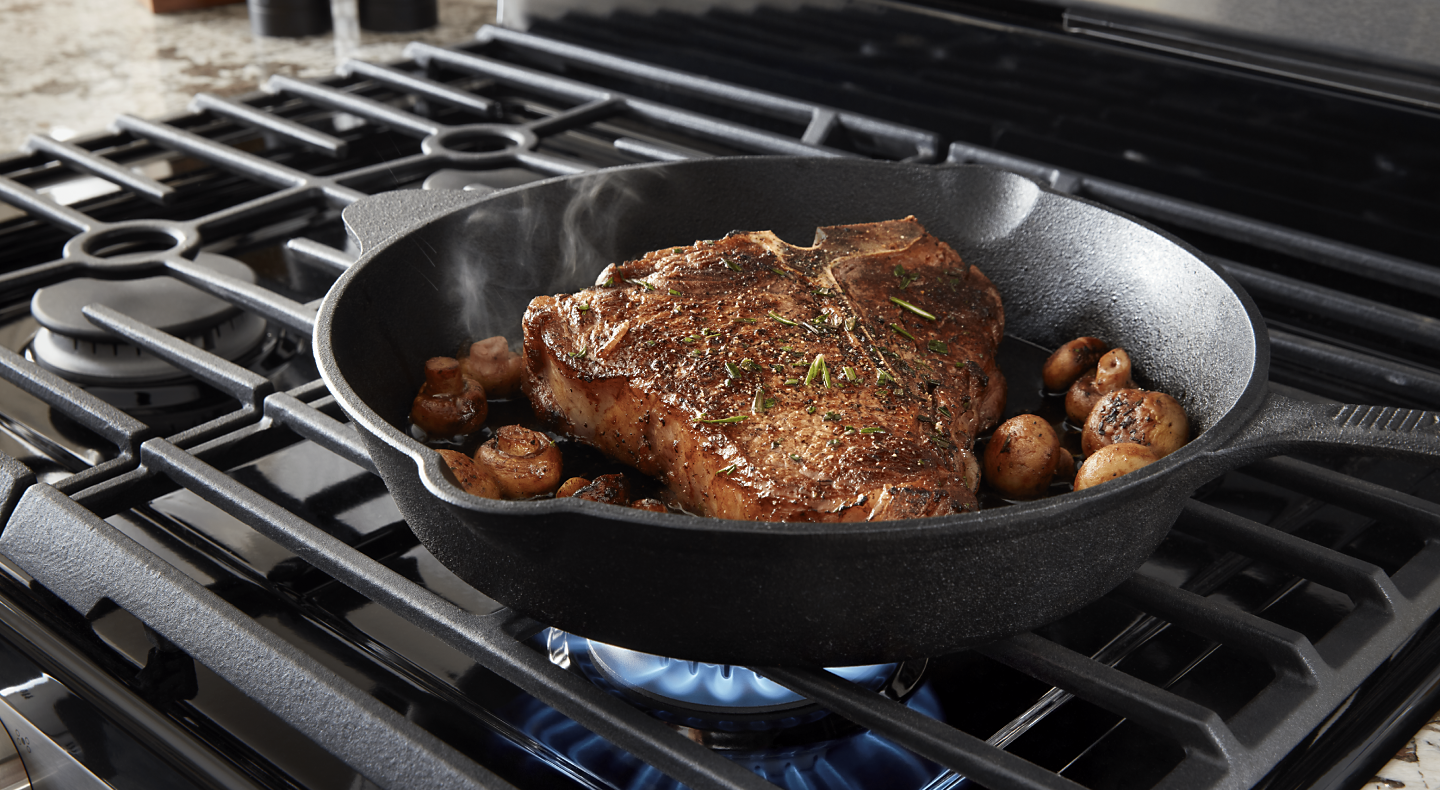 T-bone steak simmering on a Maytag brand gas cooktop