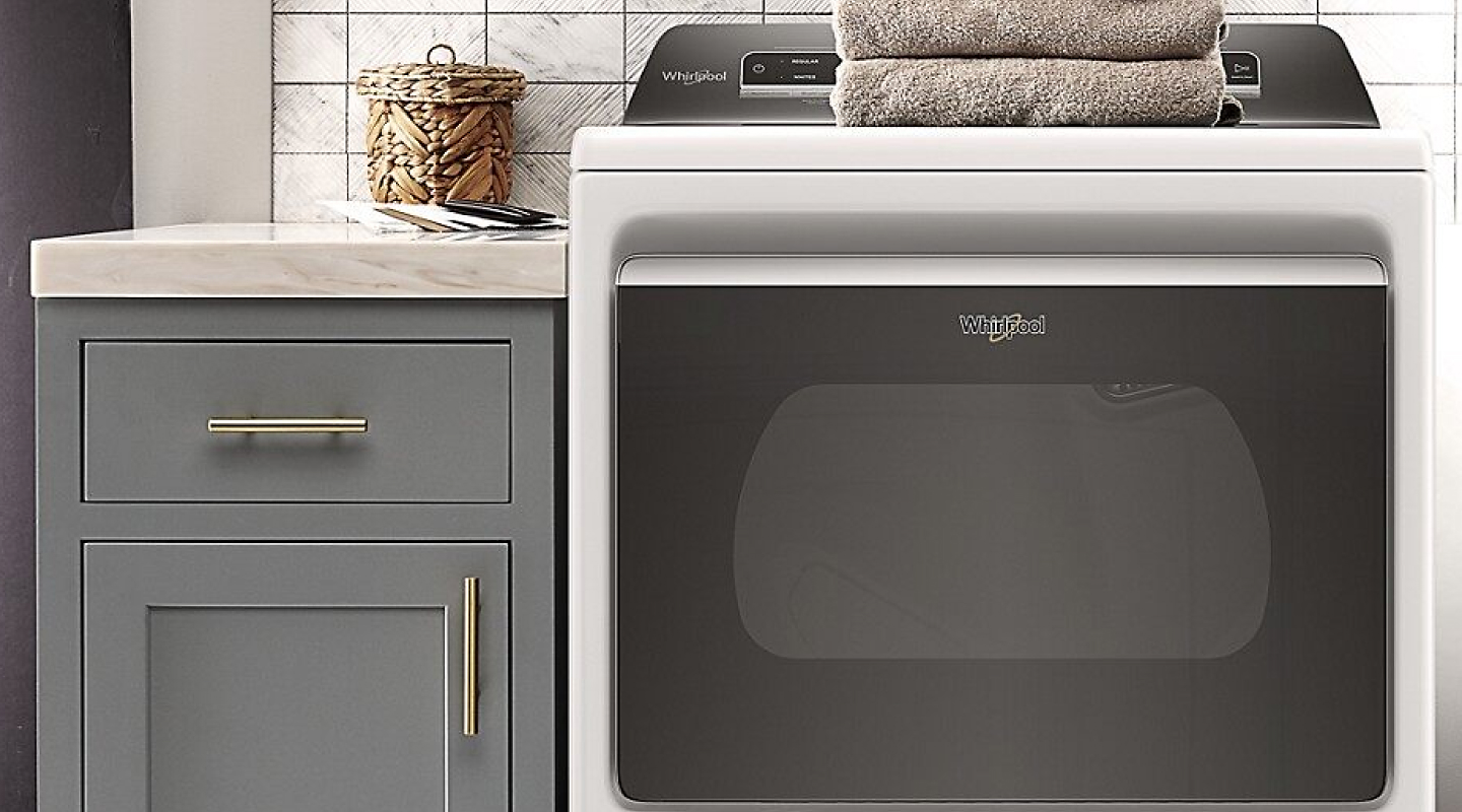 White Whirlpool® dryer next to blue-gray cabinet.