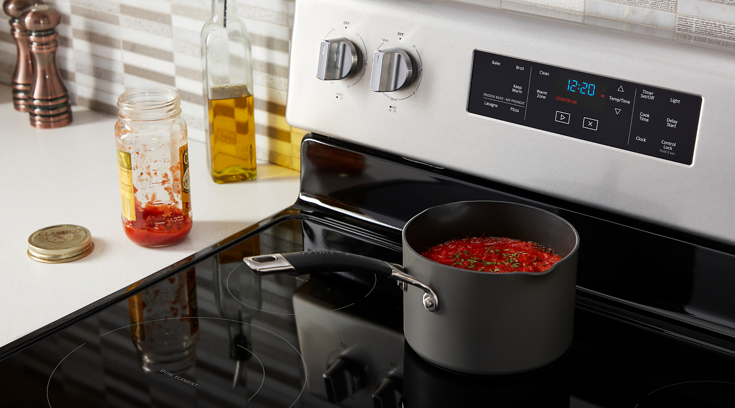 A cooking pot of pasta sauce on a glass stovetop