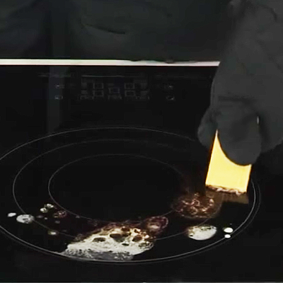 Person scraping burnt-on spills off of stovetop burner