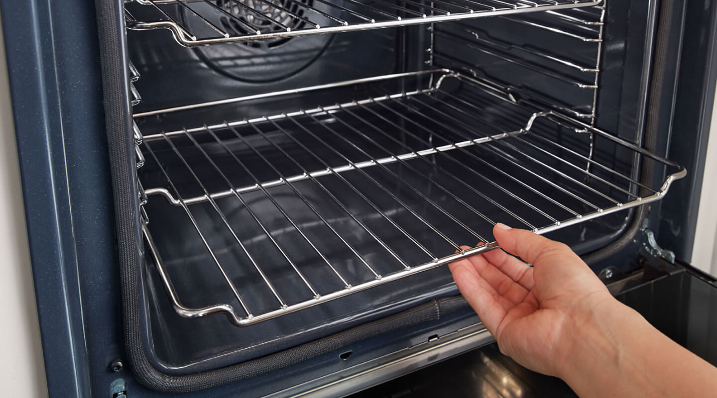 A person placing the bottom rack of an oven