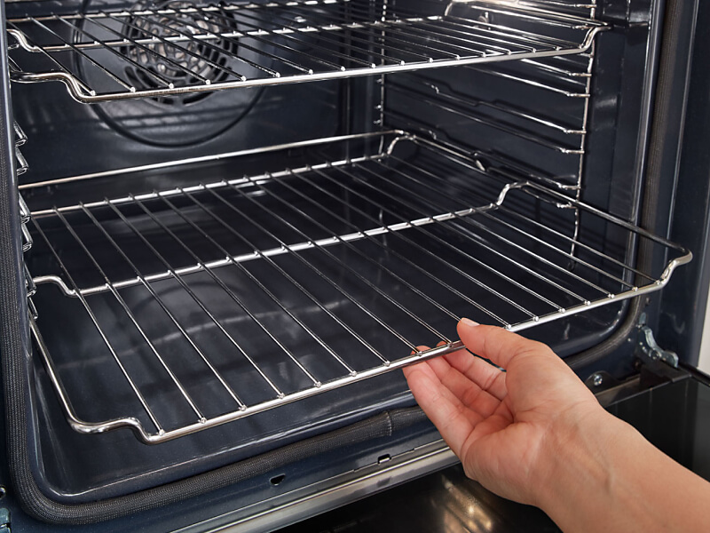 A person placing the bottom rack of an oven