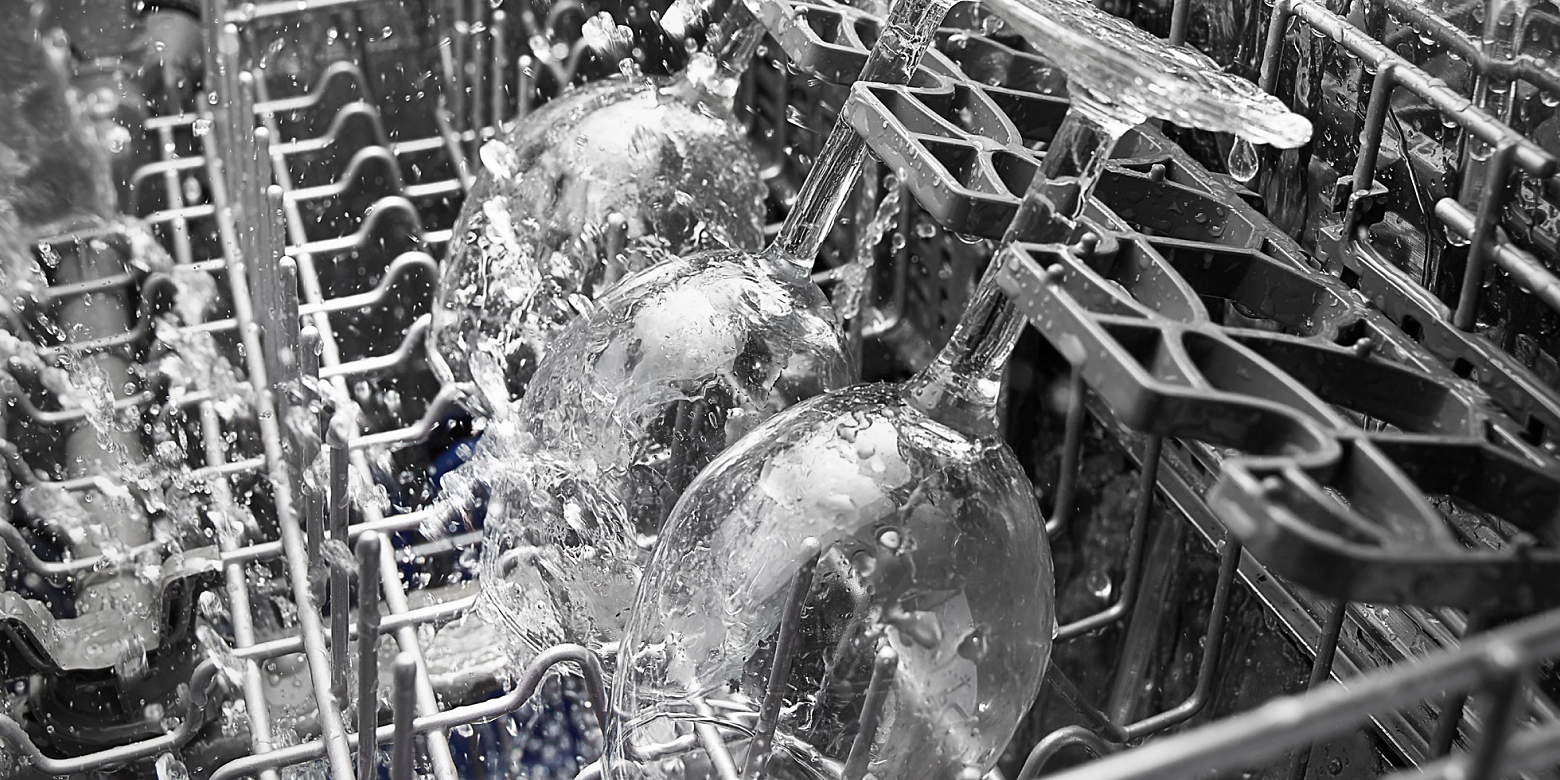 Close-up of wine glasses in dishwasher during wash cycle