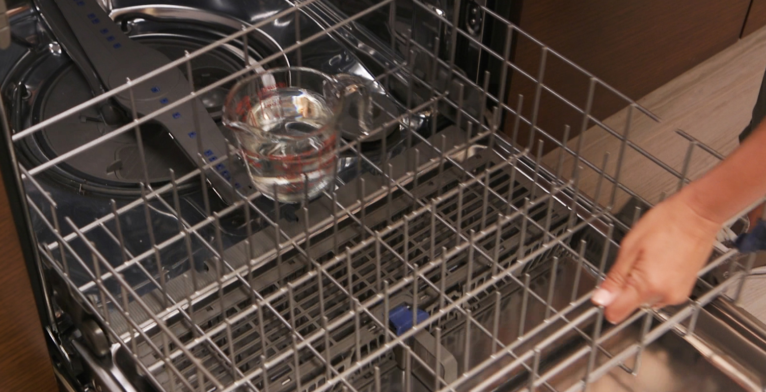 将量杯的醋放入洗碗机架上的人