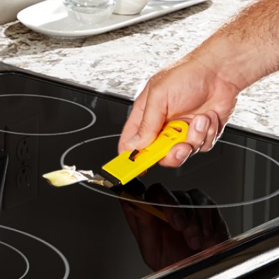 Person scraping a Whirlpool® induction cooktop.