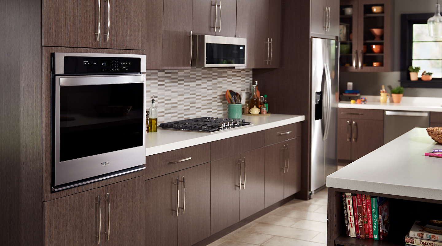 Stainless steel built-in wall oven in a kitchen with dark wood cabinets