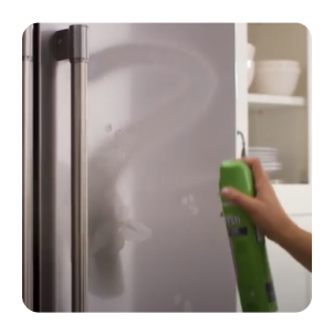 Hand spraying affresh® stainless steel cleaner onto refrigerator